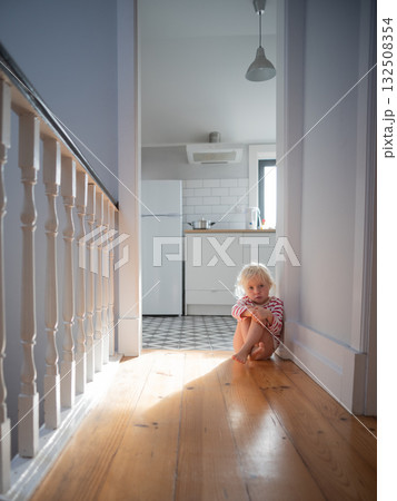 Little girl sitting alone on the floor at home, feeling scared while waiting for her parents Little girl sitting alone on the floor at home, feeling scared while waiting for her parents 132508354