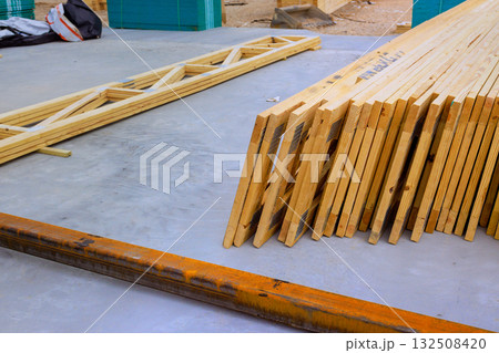 Neatly stacked wooden roofing joins planks nearby tools preparation for building at construction site. Neatly stacked wooden roofing joins planks nearby tools preparation for building at construction site. 132508420
