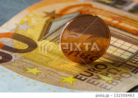 Five euro cent coin standing on fifty euro banknote, symbolizing savings, finance, and economy 132508463