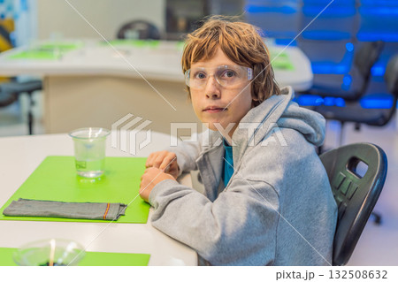 Teenage boy wearing safety glasses prepares to conduct chemistry experiments, representing STEM education, curiosity, and the excitement of hands-on scientific discovery 132508632