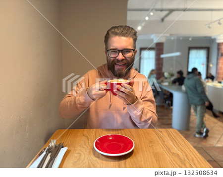 Man enjoying latte in modern cafe. Everyday relaxation, morning ritual and cozy coffee culture in urban lifestyle setting. Man enjoying latte in modern cafe. Everyday relaxation, morning ritual and cozy coffee culture in urban lifestyle setting. 132508634