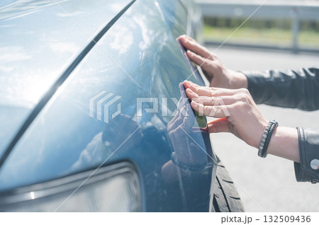 A Caucasian man inspects damage to his car.  132509436