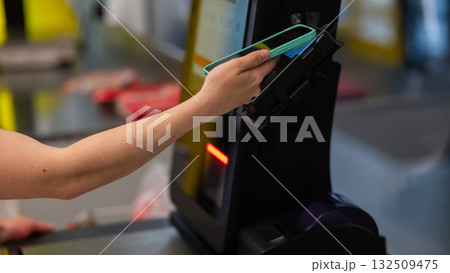 A woman pays using her smartphone at a self-checkout.  132509475