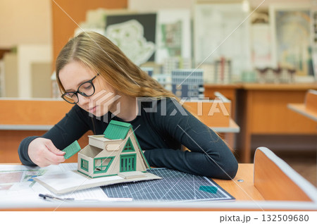Caucasian young woman making a model of a building. Student of the construction university. Caucasian young woman making a model of a building. Student of the construction university. 132509680