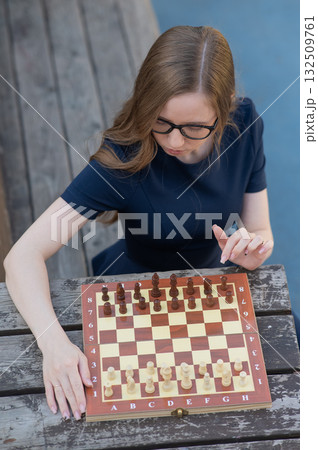 Caucasian woman playing chess outdoors.  132509761