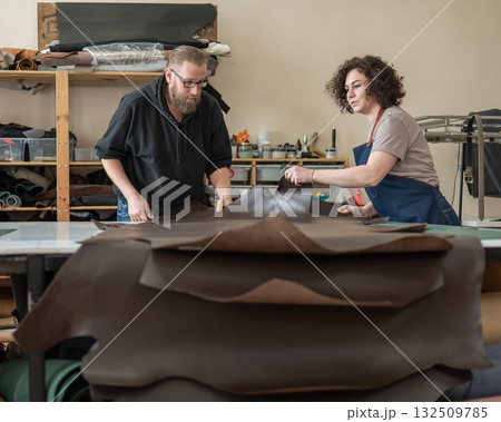 A man and a woman work as tanners in a workshop. A man and a woman work as tanners in a workshop. 132509785
