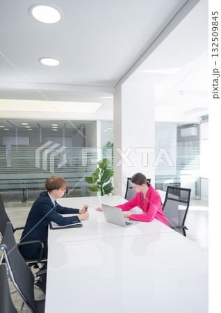 Man and woman talking while sitting at desk in office. Man and woman talking while sitting at desk in office. 132509845