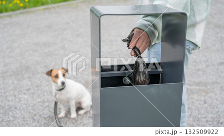 Responsible Dog Owner Disposing of Waste in Park Bin. Responsible Dog Owner Disposing of Waste in Park Bin. 132509922