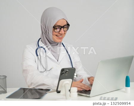 Female doctor in hijab talking to patient via video link on laptop. Female doctor in hijab talking to patient via video link on laptop. 132509954