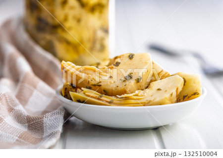 Pickled artichoke in bowl on white table. 132510004