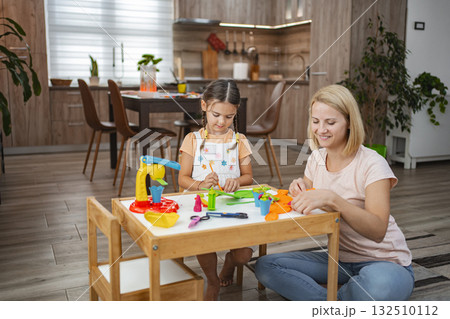 Mother and daughter enjoy playing together with plasticine 132510112