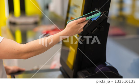 A woman pays using her smartphone at a self-checkout.  132510135