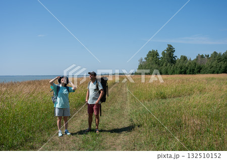 Caucasian couple hiking with backpacks on the seashore. Caucasian couple hiking with backpacks on the seashore. 132510152