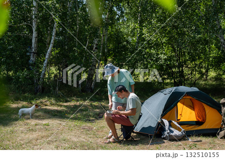 Caucasian man working on laptop in camping. Couple relaxing in nature.  132510155
