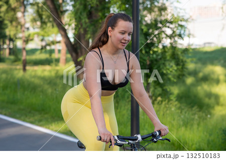 Curvy Caucasian Woman Riding Bicycle in Park.  132510183