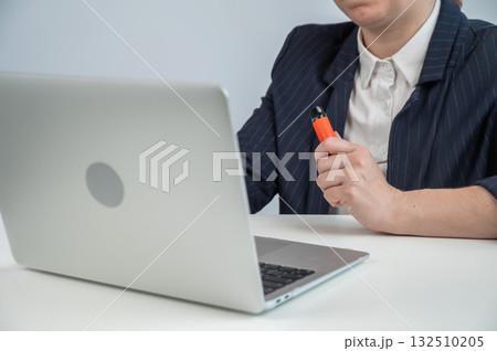 Faceless businesswoman smokes disposable vape and works on laptop. Faceless businesswoman smokes disposable vape and works on laptop. 132510205