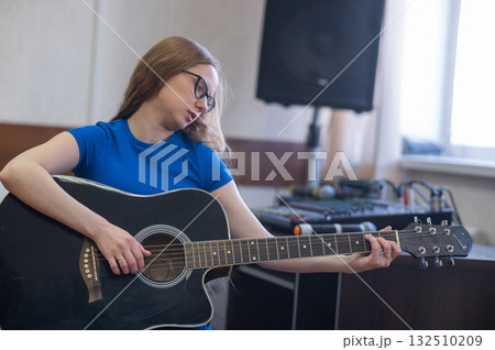 Young woman playing guitar in recording studio. Young woman playing guitar in recording studio. 132510209