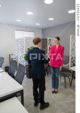 Caucasian man and woman greeting and shaking hands in office. Caucasian man and woman greeting and shaking hands in office. 132510221