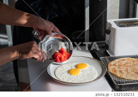 Chef serves fried eggs in a cafe.  132510233