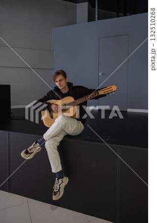 Caucasian man playing guitar while sitting on stage. Caucasian man playing guitar while sitting on stage. 132510268