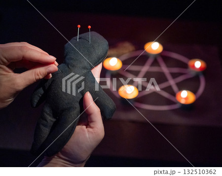 Woman sticking pins into voodoo doll. Woman sticking pins into voodoo doll. 132510362