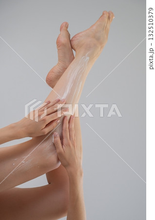 Woman applying moisturizer to her legs. White background. Woman applying moisturizer to her legs. White background. 132510379