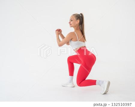 Young woman doing lunges on white cyclorama background. Vertical video. Young woman doing lunges on white cyclorama background. Vertical video. 132510397