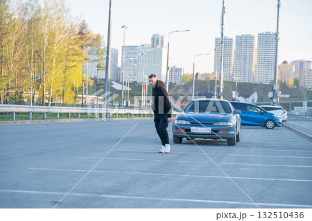 Caucasian man pulling a car with a rope. Caucasian man pulling a car with a rope. 132510436
