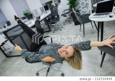 Caucasian woman having fun and lying on office chair. Caucasian woman having fun and lying on office chair. 132510444