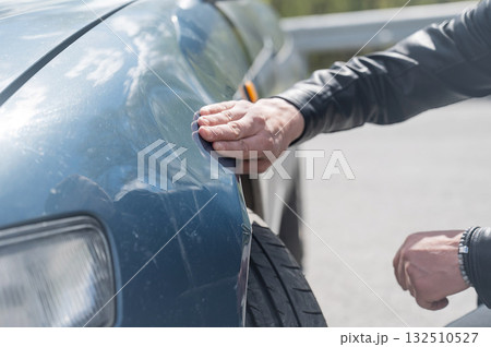 A Caucasian man inspects damage to his car. A Caucasian man inspects damage to his car. 132510527