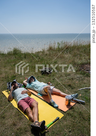 Caucasian couple relaxing during a hike on the seashore.  132510587