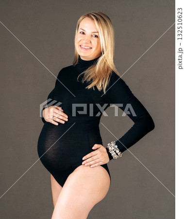 Elegant maternity photo, expecting woman in black bodysuit smiling softly. 28 week Elegant maternity photo, expecting woman in black bodysuit smiling softly. 28 week 132510623