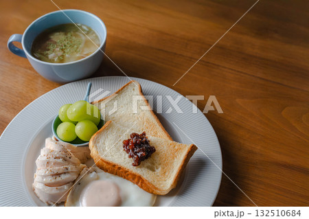 トーストと目玉焼き、鶏ハムとシャインマスカットを添えた洋風の朝食 トーストと目玉焼き、鶏ハムとシャインマスカットを添えた洋風の朝食 132510684