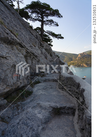 Stone path against the sea and mountains at sunset 132510831