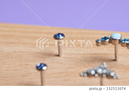 Beautiful piercing jewelry on wooden display. Macro shot. Selective focus. Beautiful piercing jewelry on wooden display. Macro shot. Selective focus. 132511074
