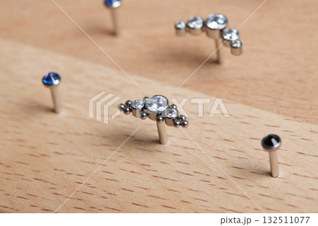 Beautiful piercing jewelry on wooden display. Macro shot. Selective focus. Beautiful piercing jewelry on wooden display. Macro shot. Selective focus. 132511077