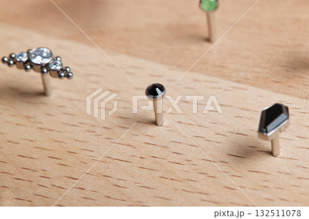 Beautiful piercing jewelry on wooden display. Macro shot. Selective focus. Beautiful piercing jewelry on wooden display. Macro shot. Selective focus. 132511078