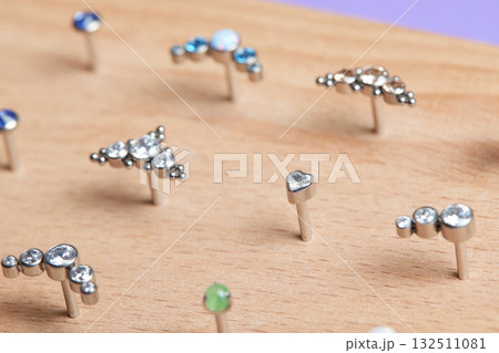 Beautiful piercing jewelry on wooden display. Macro shot. Selective focus. 132511081
