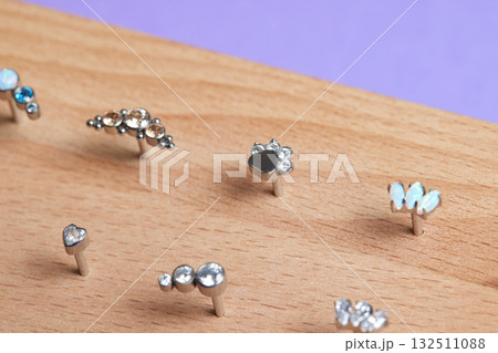 Beautiful piercing jewelry on wooden display. Macro shot. Selective focus. Beautiful piercing jewelry on wooden display. Macro shot. Selective focus. 132511088