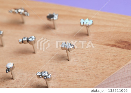 Beautiful piercing jewelry on wooden display. Macro shot. Selective focus. Beautiful piercing jewelry on wooden display. Macro shot. Selective focus. 132511093