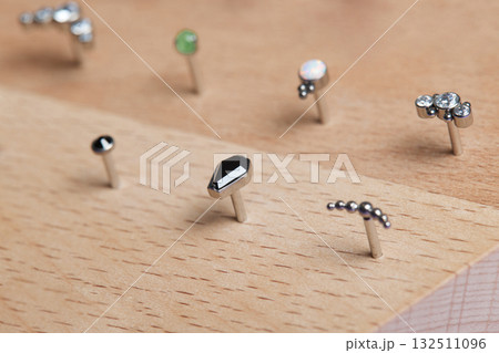 Beautiful piercing jewelry on wooden display. Macro shot. Selective focus. Beautiful piercing jewelry on wooden display. Macro shot. Selective focus. 132511096