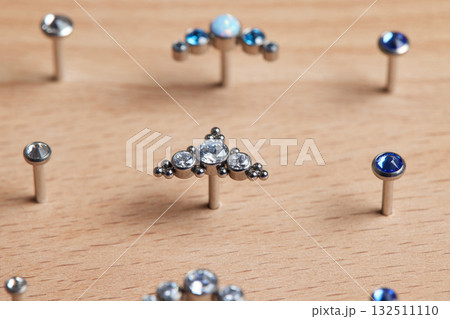 Beautiful piercing jewelry on wooden display. Macro shot. Selective focus. Beautiful piercing jewelry on wooden display. Macro shot. Selective focus. 132511110