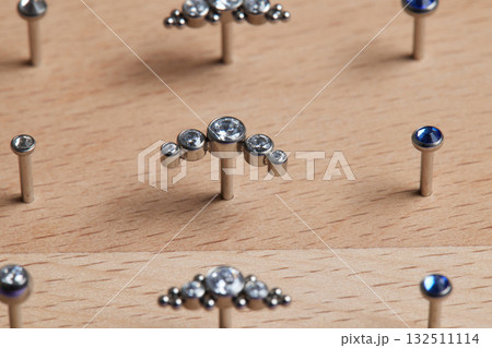 Beautiful piercing jewelry on wooden display. Macro shot. Selective focus. Beautiful piercing jewelry on wooden display. Macro shot. Selective focus. 132511114