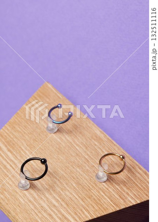 Beautiful piercing jewelry on wooden display. Macro shot. Selective focus. Beautiful piercing jewelry on wooden display. Macro shot. Selective focus. 132511116