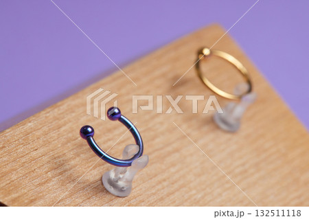 Beautiful piercing jewelry on wooden display. Macro shot. Selective focus. 132511118