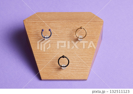 Beautiful piercing jewelry on wooden display. Macro shot. Selective focus. 132511123
