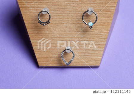 Beautiful piercing jewelry on wooden display. Macro shot. Selective focus. Beautiful piercing jewelry on wooden display. Macro shot. Selective focus. 132511146
