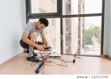 Professional window technician male managing robotic cleaning equipment, preparing automated system for servicing high-rise building exterior, demonstrating advanced maintenance technology. 132511195