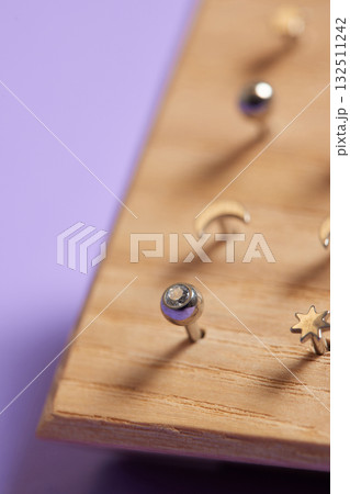 Beautiful piercing jewelry on wooden display. Macro shot. Selective focus. 132511242