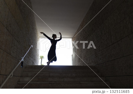 Dancer silhouetted in light exiting dark tunnel 132511685